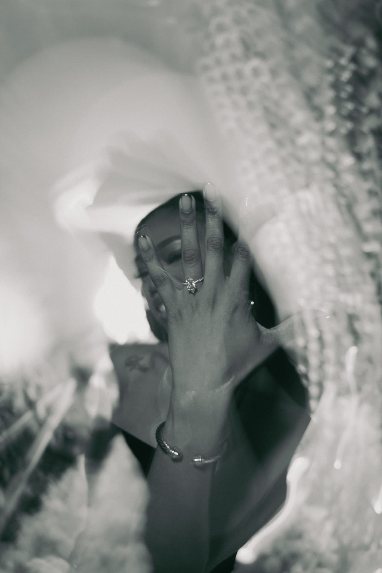 Bride shows her ring through the veil, black and white