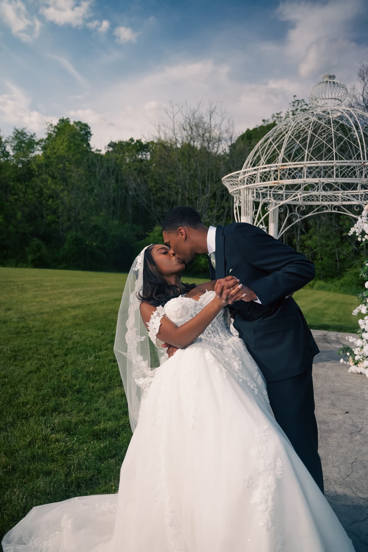 Bride and groom kiss beside a garden gazebo